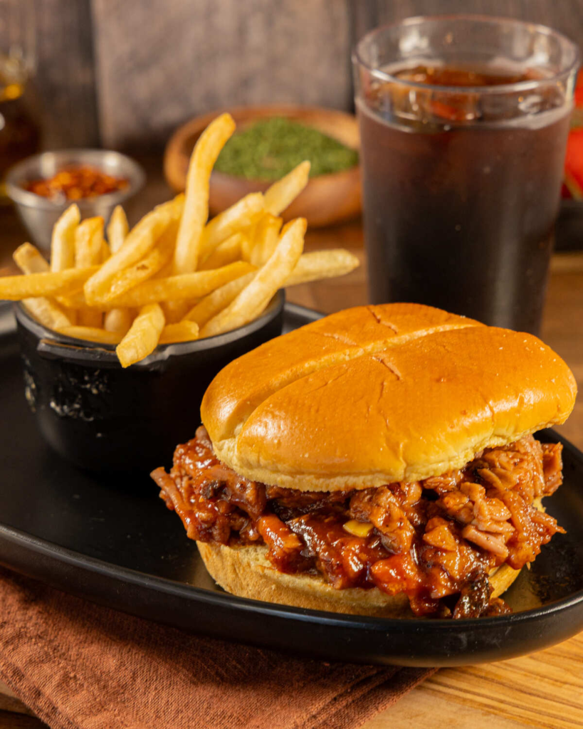 Pulled pork sandwich on potato bun with BBQ sauce and crispy onions